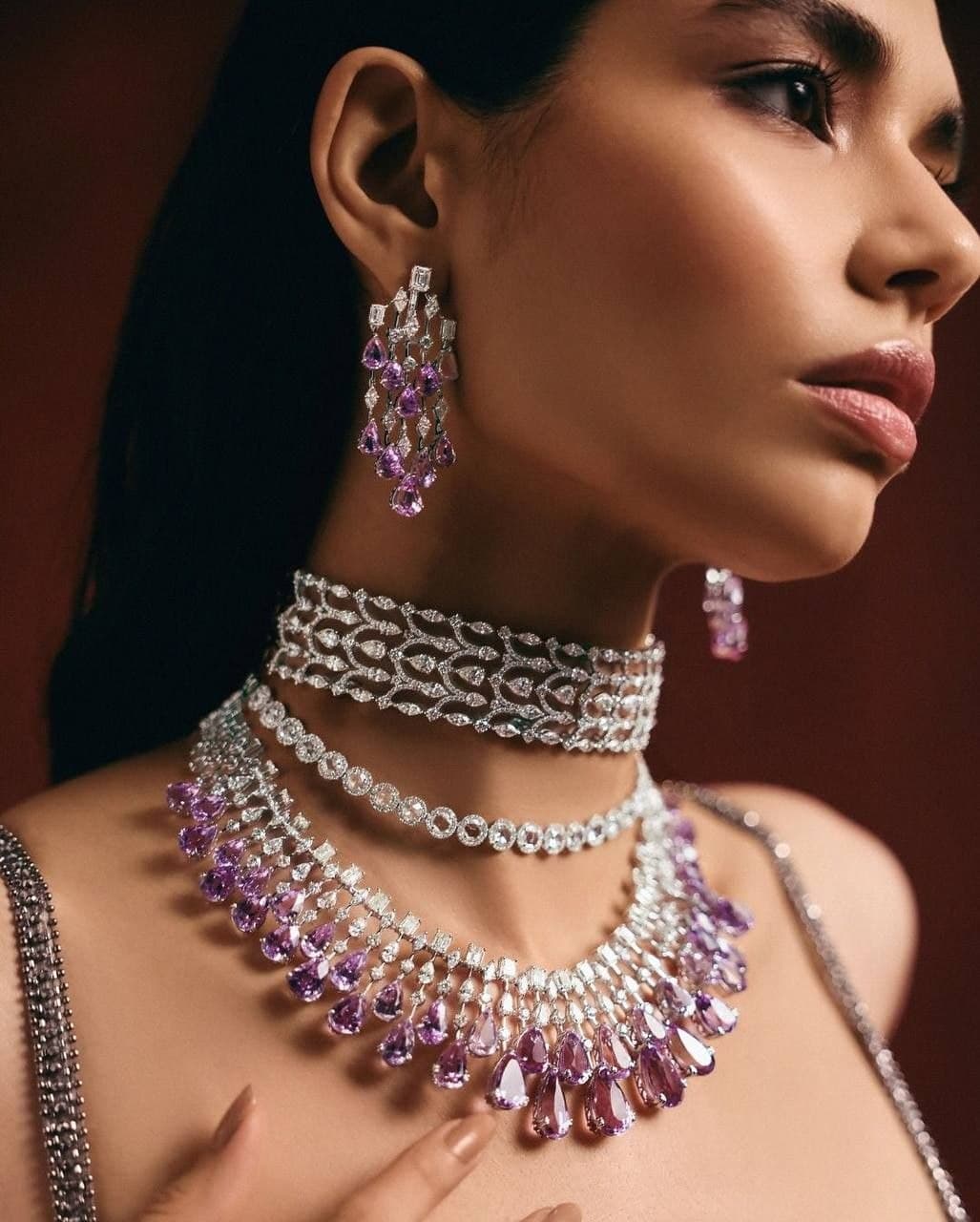 Pink sapphire chandelier earrings and layered diamond chokers against oxblood